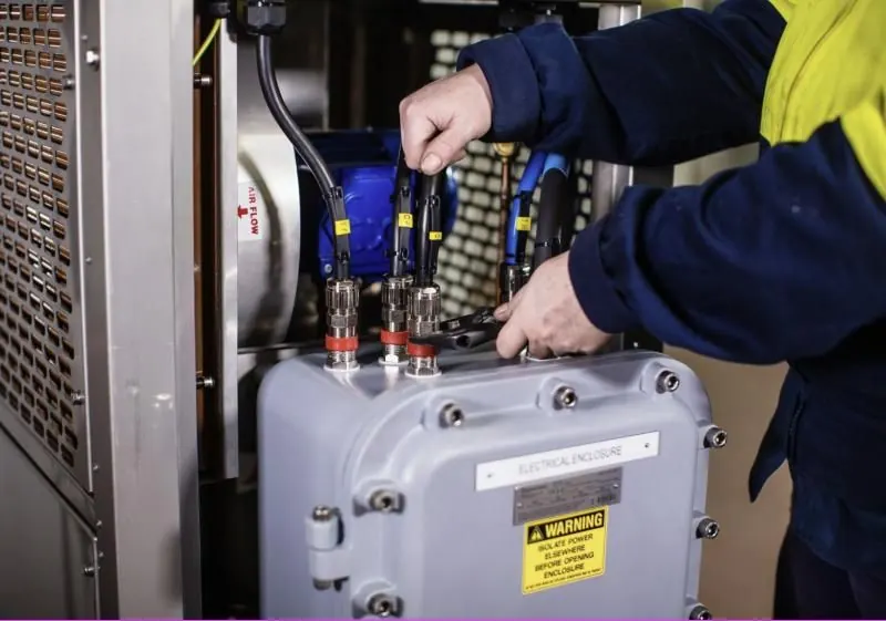 Technician fitting cable glands to an Ex electrical enclosure